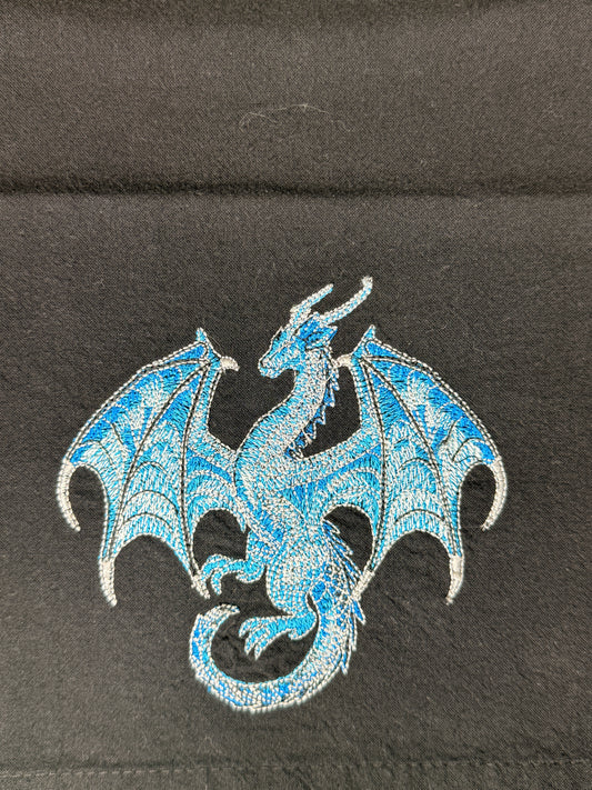A blue and silver embroidered dragon patch on a black fabric background.